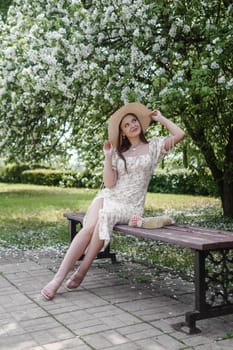 An attractive long-haired woman walks in the spring in the park of blooming apple trees. Spring portrait of a woman