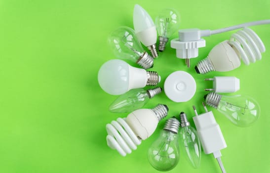 A set of different types of LED lamps isolated on a green background. Energy-saving lamps, a flashlight in the center