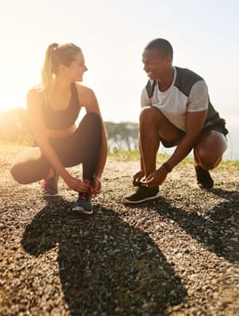 Are you ready. a fit young couple tying their shoelaces before a run outdoors