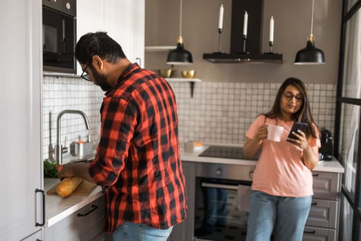 Millennial couple in quarrel and woman with smartphone ignoring each other having breakfast together at home, gadget overuse - communication problem family