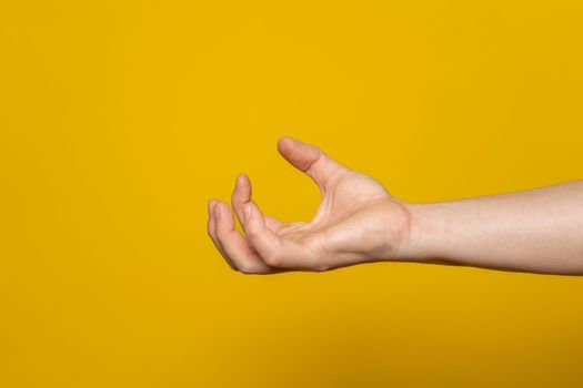 Pissed off and bloodthirsty strong man's hand in the form of a claw containing anger and aggressiveness isolated on a yellow background