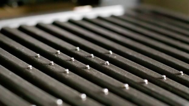 Black electric grill grate, textured background. The surface of the electric grill. Pollution of the surface of the electric stove. Close-up of a home electric grill, in the kitchen. BBQ