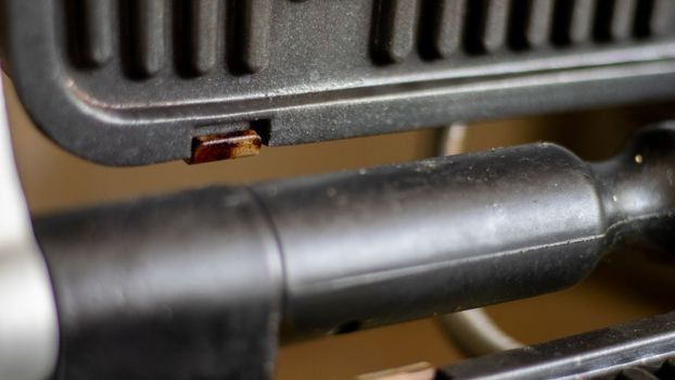 Black electric grill grate, textured background. The surface of the electric grill. Pollution of the surface of the electric stove. Close-up of a home electric grill, in the kitchen. BBQ