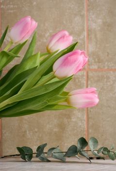 Empty decorative stand, eucalyptus branches and a bouquet of tulips on the table, background for showcasing cosmetics and products.