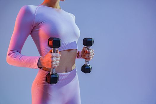 Woman doing exercises with dumbbells on studio background . Sport and healthy lifestyle