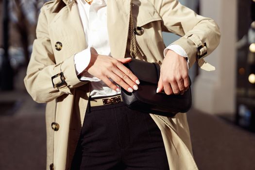 Close up of woman is opening her bag while standing on city street. High quality photo