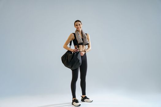 Woman wearing sportswear with sports bag after training on studio background. High quality photo