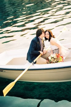 Man kisses woman on the cheek while sitting in a boat with oars. High quality photo