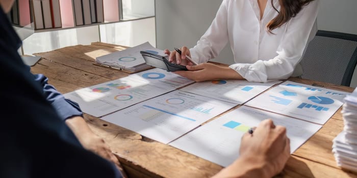 female and male accountant use calculator to calculate the company financial results with on data network connection of finance and and analytical research, income, tax and business growth.