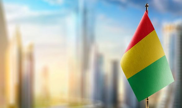 Small flags of the Guinea on an abstract blurry background.