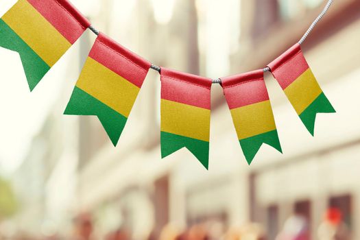 A garland of Guinea national flags on an abstract blurred background.