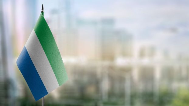 Small flags of the Sierra Leone on an abstract blurry background.