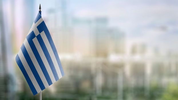 Small flags of the Greece on an abstract blurry background.