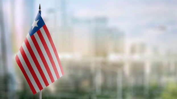 Small flags of the Liberia on an abstract blurry background.