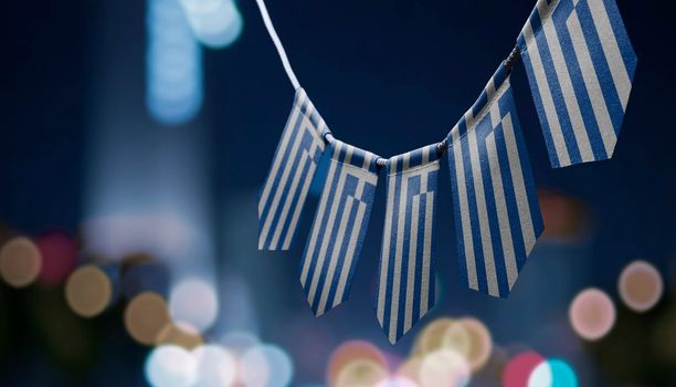 A garland of Greece national flags on an abstract blurred background.