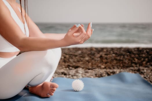 Woman yoga sea. Young woman with braids dreadlocks in white swimsuit and boho style braclets practicing outdoors on yoga mat by the ocean on sunny day. Women's yoga fitness routine. Healthy lifestyle, harmony