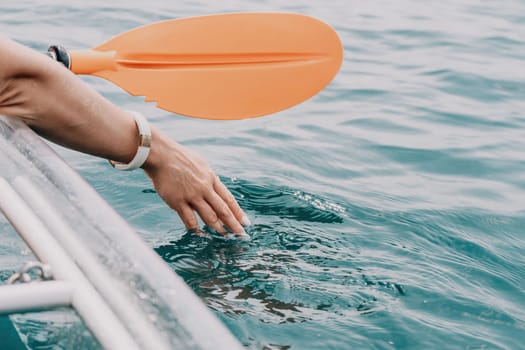 Woman in kayak back view. Happy young woman with long hair floating in transparent kayak on the crystal clear sea. Summer holiday vacation and cheerful female people having fun on the boat.