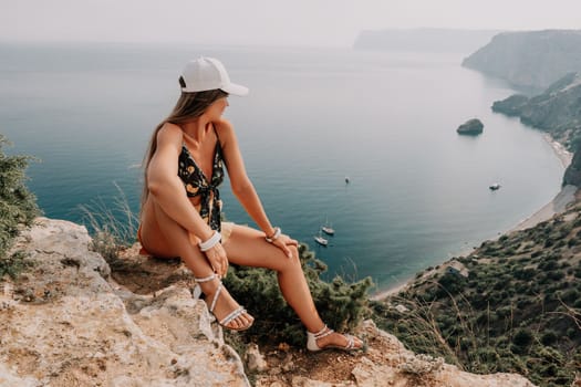 Woman travel sea. Happy tourist taking picture outdoors for memories. Woman traveler looks at the edge of the cliff on the sea bay of mountains, sharing travel adventure journey.