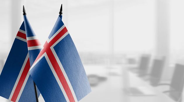 Small flags of the Iceland on an abstract blurry background.