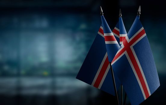 Small flags of the Iceland on an abstract blurry background.