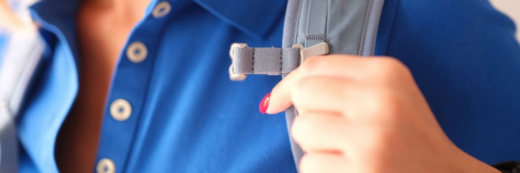 Closeup of woman in blue polo and gray harness of sports backpack. Choosing quality backpack concept