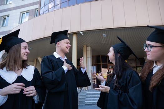 Happy students in graduate gown communicate in sign language