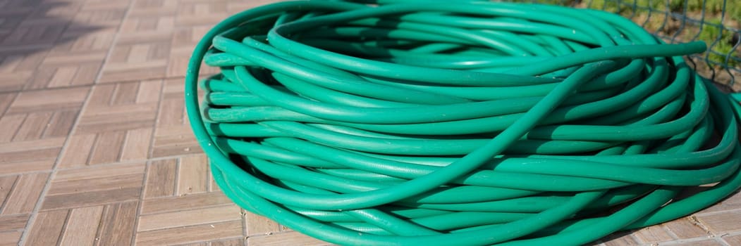 Bundle of garden hose on lawn in summer garden. Watering hose for garden