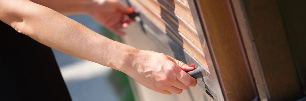 Women hands open outdoor wooden blinds. Trade shutters open concept