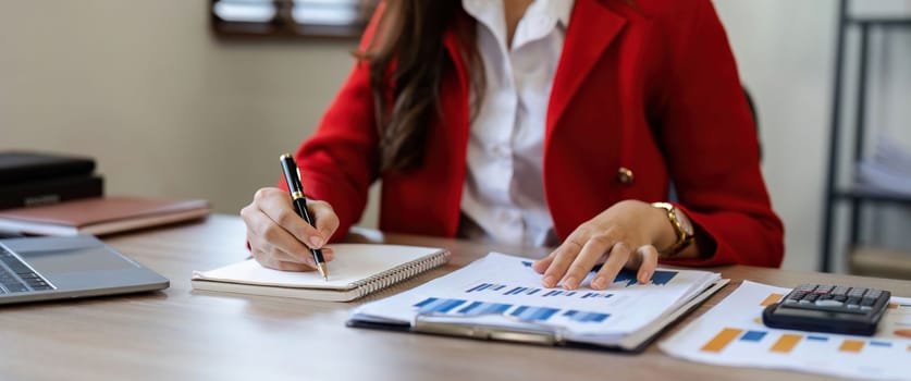 close-up shot of accountant using calculator while taking notes on office desk.