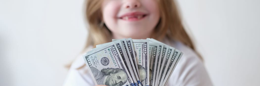Portrait of happy girl holding cash dollars. Pocket money and earnings