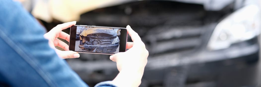 Person photography burnt car on smartphone. Assessment of insurance damage after car fire