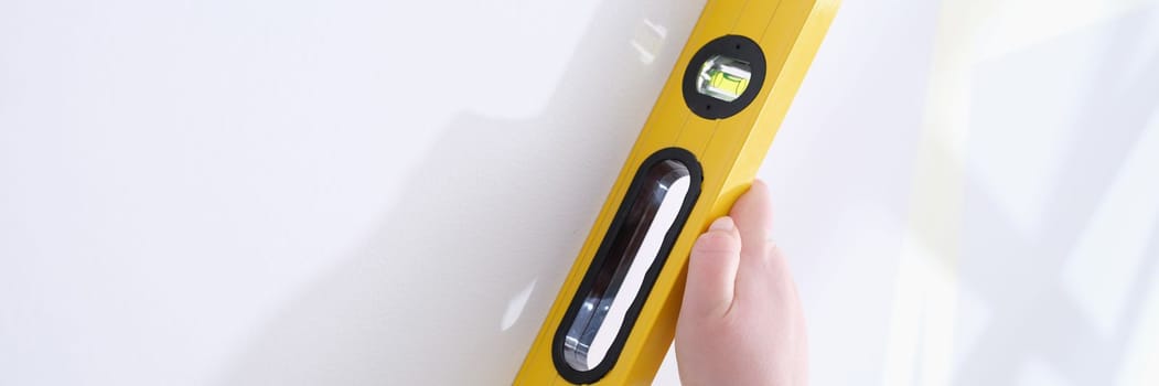 Professional yellow measuring device for level and evenness of wall. Builder makes repairs in apartment concept