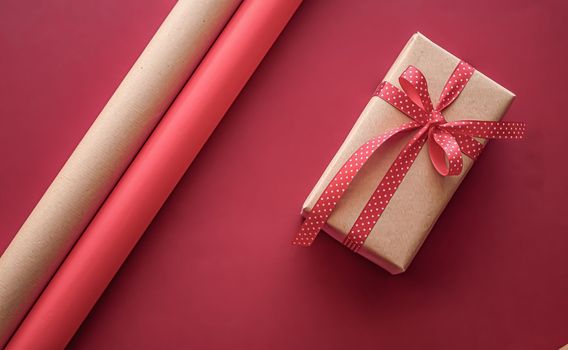 Gifts preparation, birthday and holidays gift giving, craft paper and ribbons for gift boxes on coral background as wrapping tools and decorations, diy presents as holiday flat lay design.