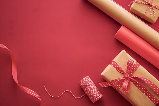 Gifts preparation, birthday and holidays gift giving, craft paper and ribbons for gift boxes on coral background as wrapping tools and decorations, diy presents as holiday flat lay design.