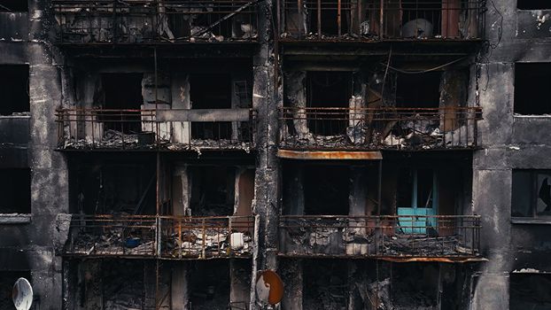 A burnt-out high-rise in the war zone. Damage to a residential building as a result of artillery shelling. War in residential areas, broken windows and burned apartments. Armed conflict in Ukraine.