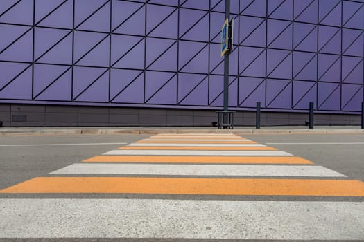 Pedestrian crosswalk on a renovated paved road, to the beginning of the shopping complex. Pedestrian crosswalk on the street for safety, white and yellow stripes