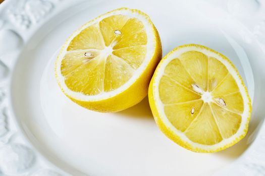 Yellow fresh lemon cut in half on white plate