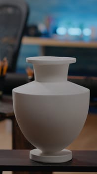 Close up of white vase on table in art studio room at home while african american woman drawing design in background. Black artist with fine art inspiration for masterpiece project