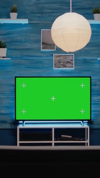 Empty modern room designed with green screen on tv at home. Nobody in area with digital technology and chroma key for isolated mockup display with copy space background and equipment