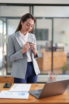 Female employee with coffee at workplace. Businesswoman preparing economic report