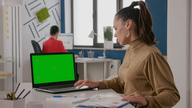 Business woman working with green screen on laptop, computer with mock up background and isolated copy space template on chroma key. Worker using chroma-key mockup on screen display.