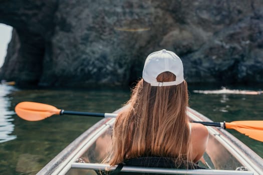 Woman in kayak back view. Happy young woman with long hair floating in transparent kayak on the crystal clear sea. Summer holiday vacation and cheerful female people having fun on the boat.