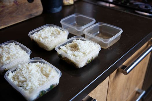 Meal prep. Stack of home cooked rice and chicken dinners in containers ready to be frozen for later use as quick and easy ready meals. Food prepping for healthy dieting close up