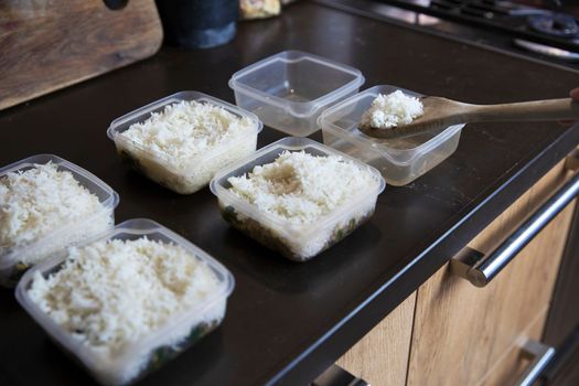 Meal prep. Stack of home cooked rice and chicken dinners in containers ready to be frozen for later use as quick and easy ready meals. Food prepping for healthy dieting close up