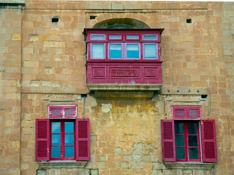 Fragment of the building's facade with traditional wooden ornate balconies painted in Valletta, Malta. High quality photo