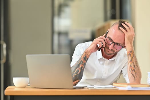 Upset male employee having serious conversation on smartphone, arguing with client or customer.