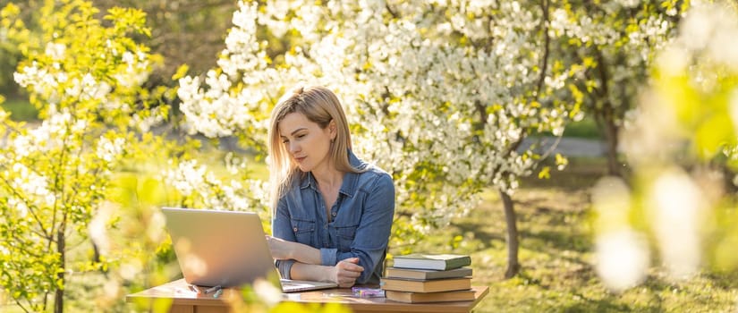 Girl with a laptop on the spring meadow