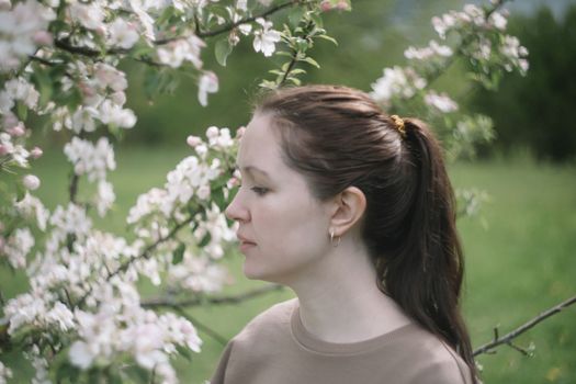 beautiful young woman near the blossoming spring tree. Emotional woman portrait