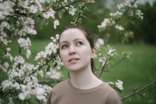 beautiful young woman near the blossoming spring tree. Emotional woman portrait
