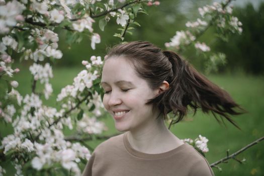 beautiful young woman near the blossoming spring tree. Emotional woman portrait